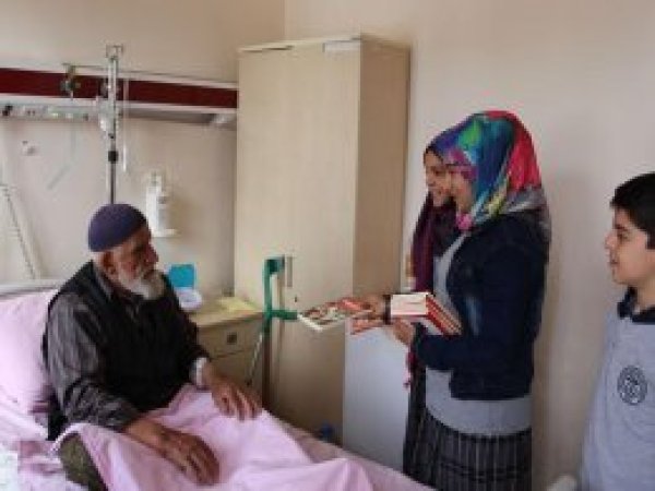 Öğrenciler hastanede hastalarla birlikte kitap okuyor